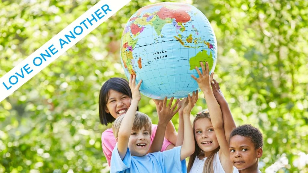 Multi-racial children smile and hold a large globe over their heads together